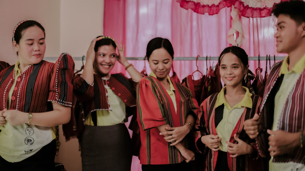 A group of teens candidly posed wearing traditional clothes made of loom